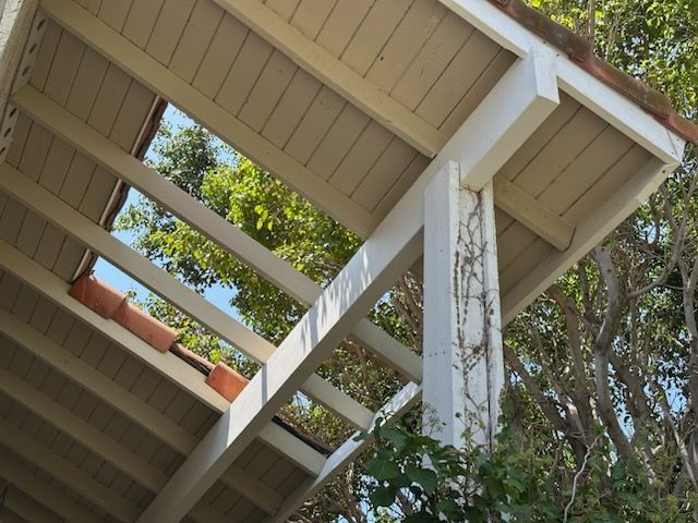White pergola with open skylight, terracotta tile roof, and climbing vines.