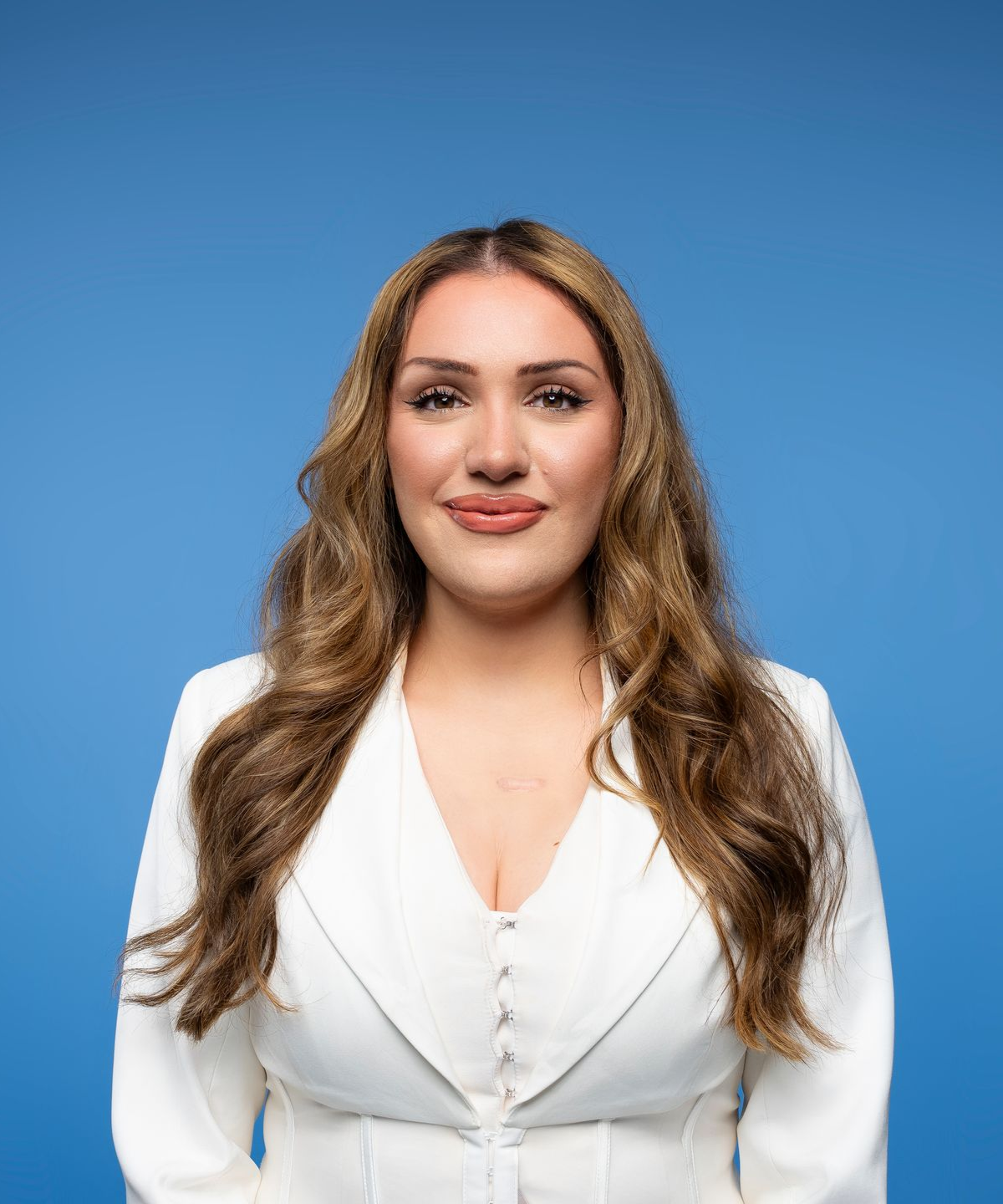Woman with brown hair smiling in a white blazer 