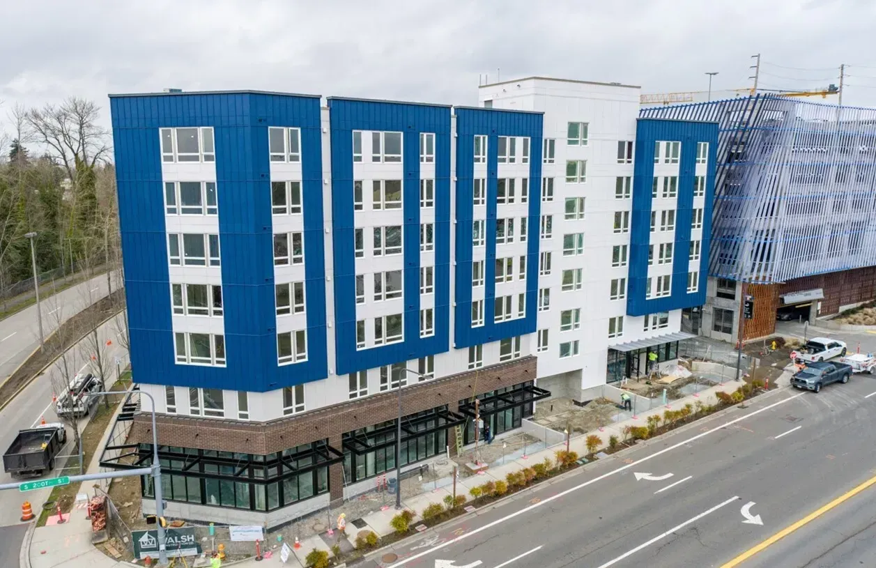 Modern apartment building with blue and white facade. Construction ongoing. Street view.