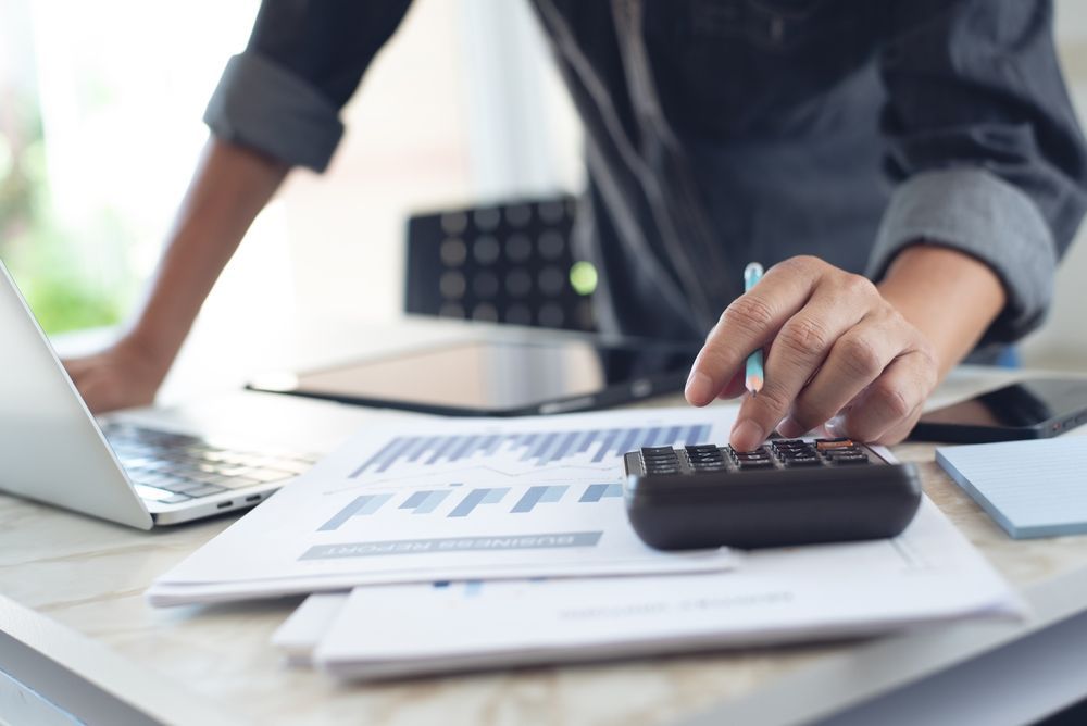 A man is using a laptop and a calculator at a desk.