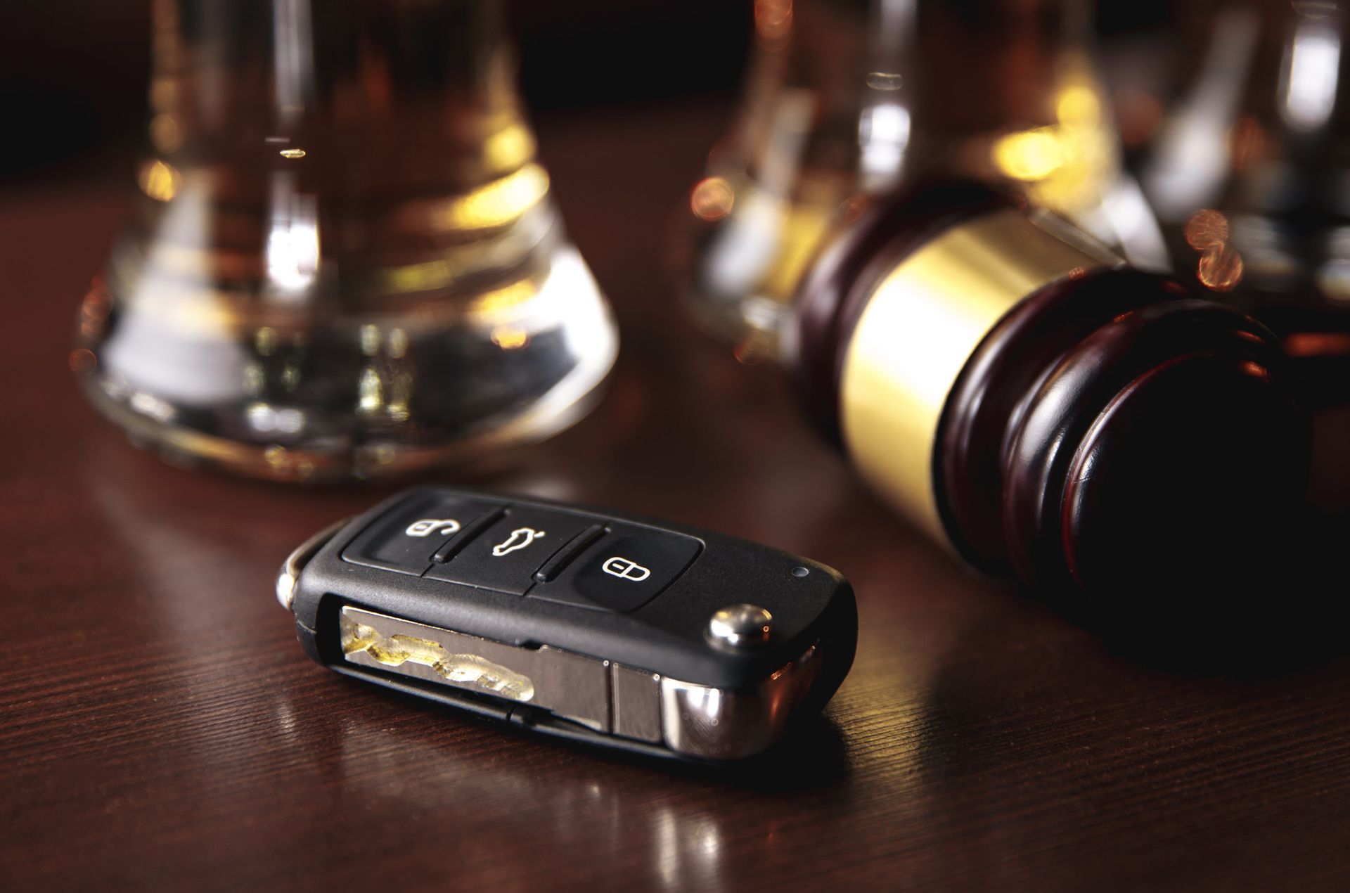 Car key fob on a table beside a gavel and a brass bell, suggesting legal or courtroom setting