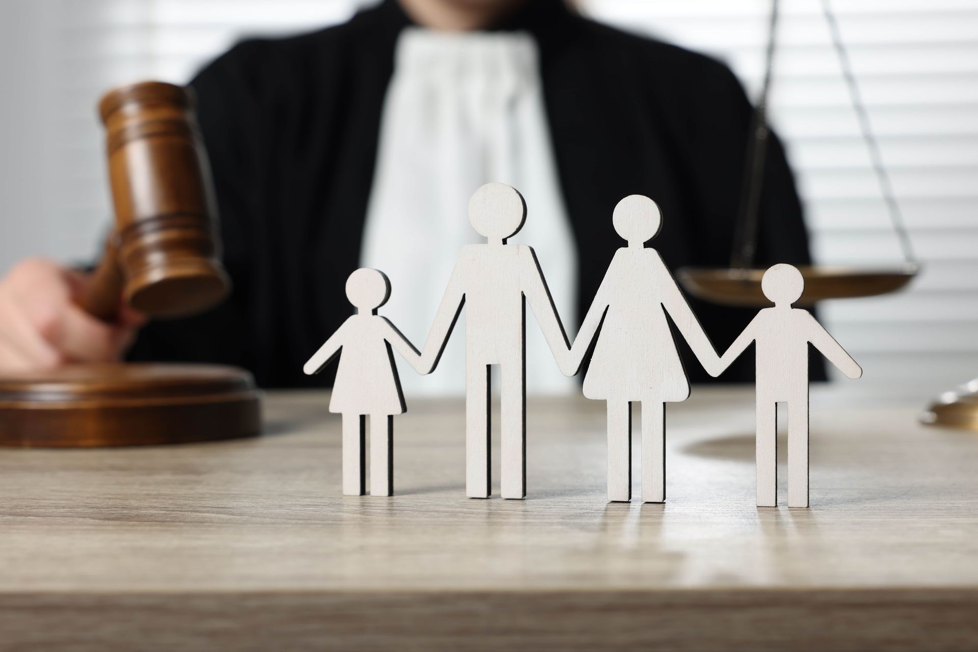 Paper family figures in a courtroom with a judge’s gavel in the background, symbolizing custody or family law.