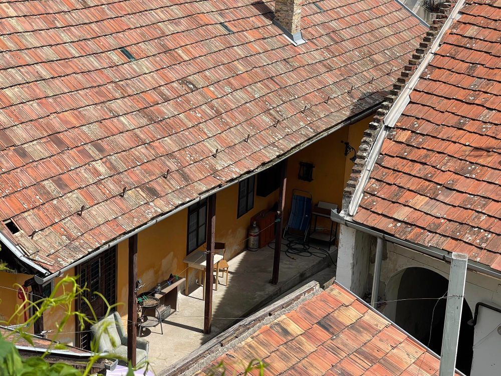 Overhead view of several buildings with red tile roofs. A yellow building has a shaded porch area.