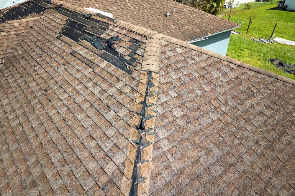 Close-up of weathered brown asphalt shingle roof with damage and missing shingles.