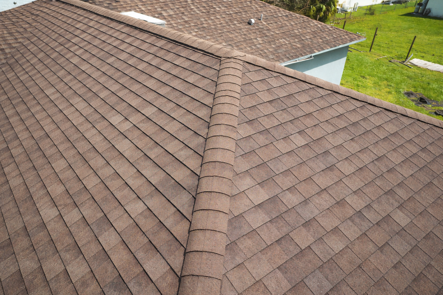Brown asphalt shingle roof with a central ridge.