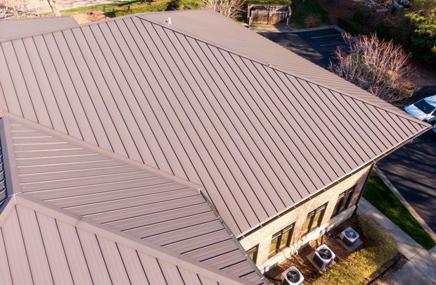 Brown metal roof of a building with visible seams, angled view.