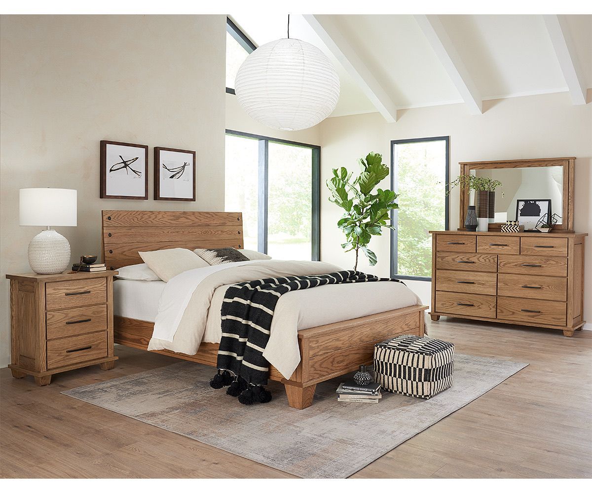 Bedroom set with light wood bed frame, nightstand, and dresser. Neutral tones, rug, large window, and decorative art.