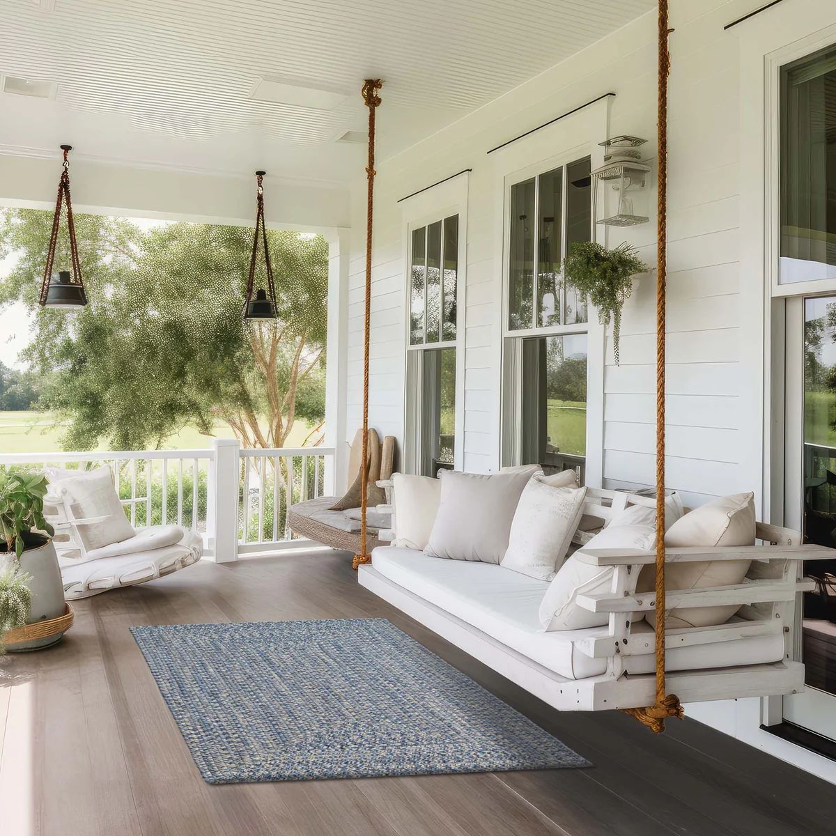 A porch with hanging swings, rug, and outdoor furniture. White and neutral tones.