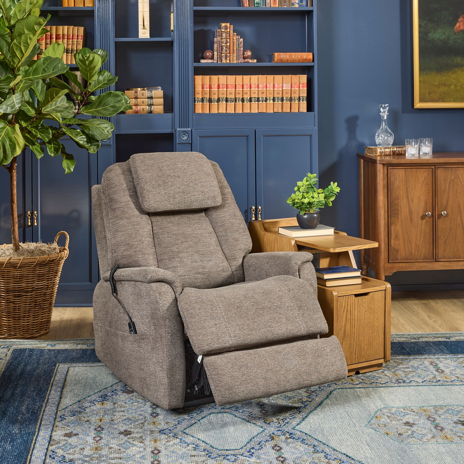 Tan recliner chair in a blue-walled room with a rug, shelves, and side tables.