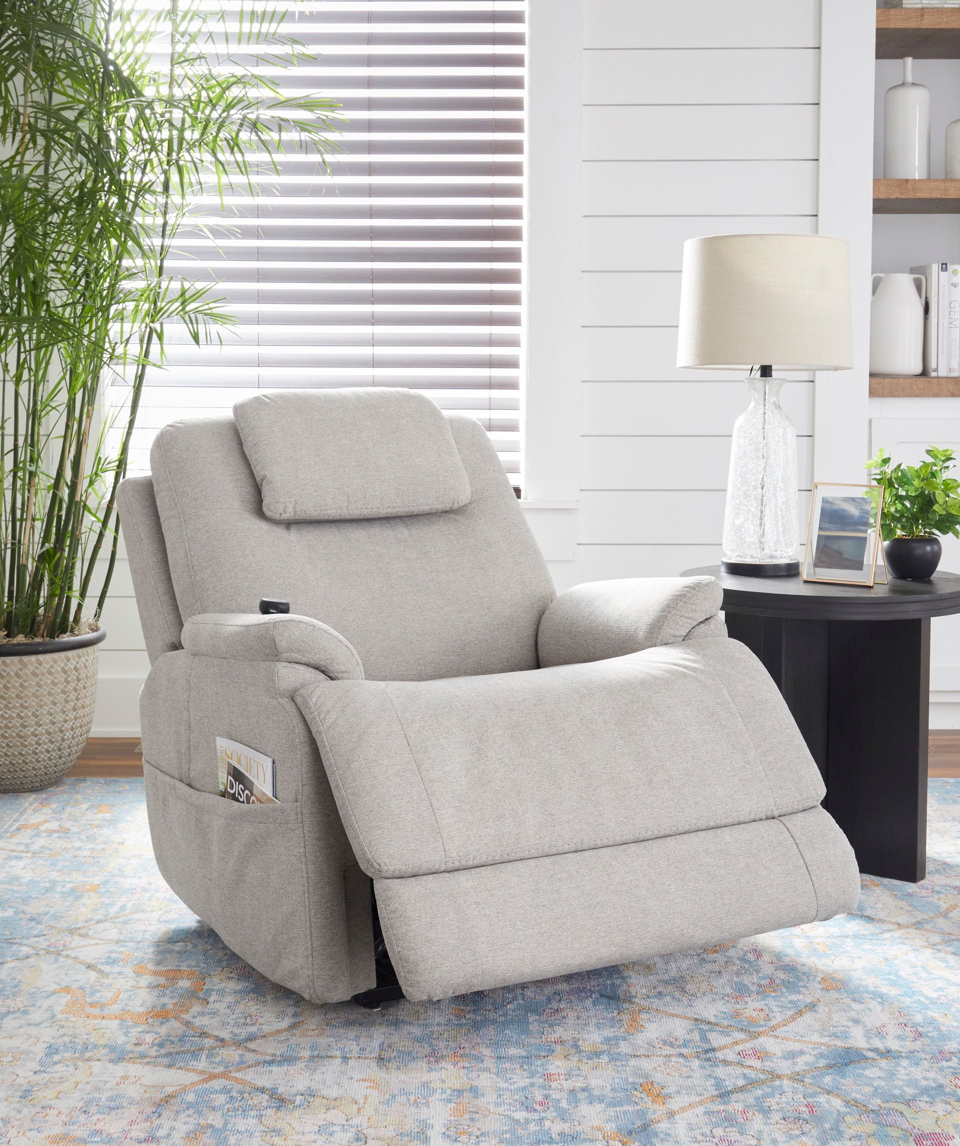 Light gray recliner chair in a living room setting, partially reclined.