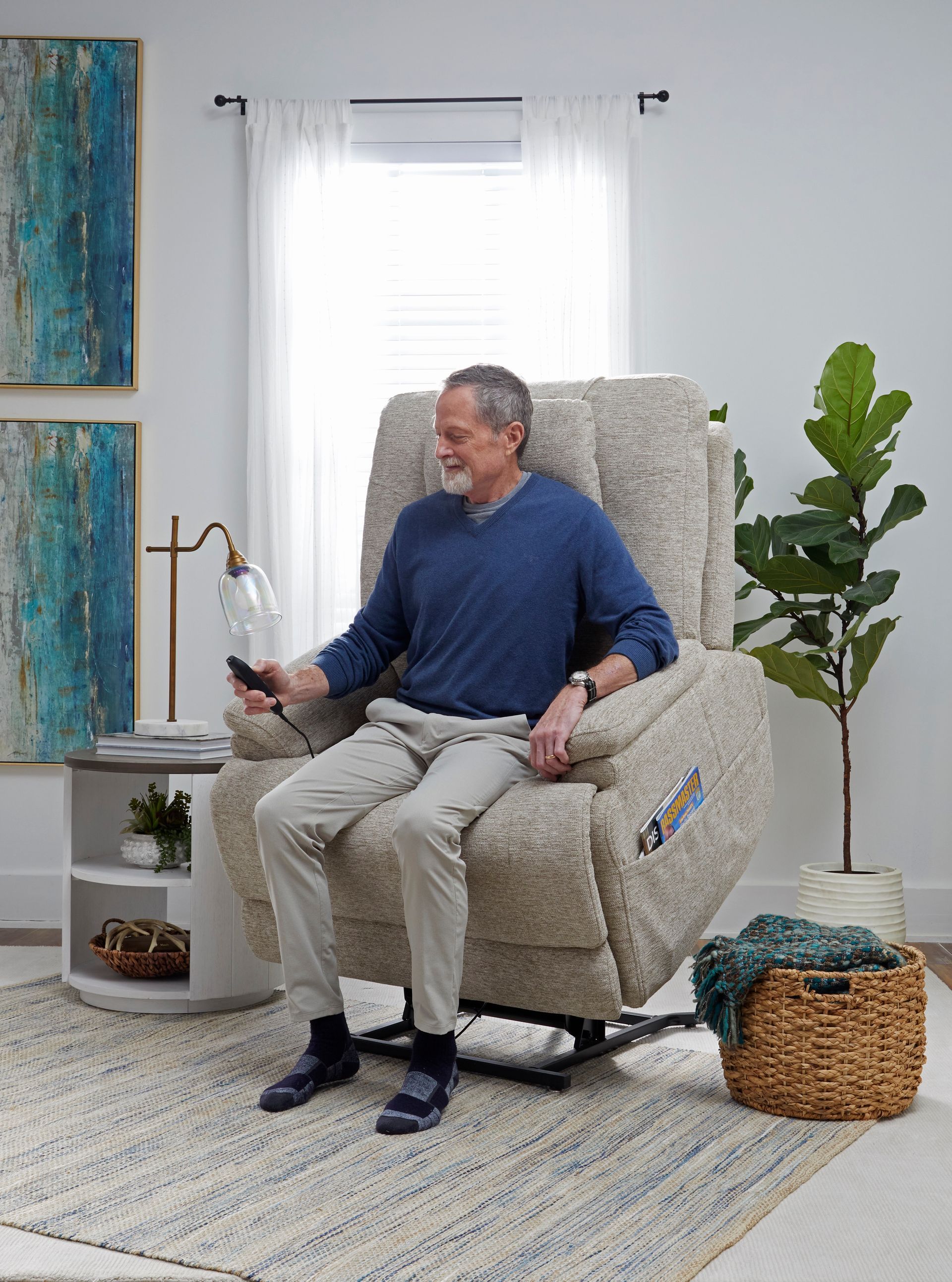 Man using remote in a beige lift chair, in a bright living room.