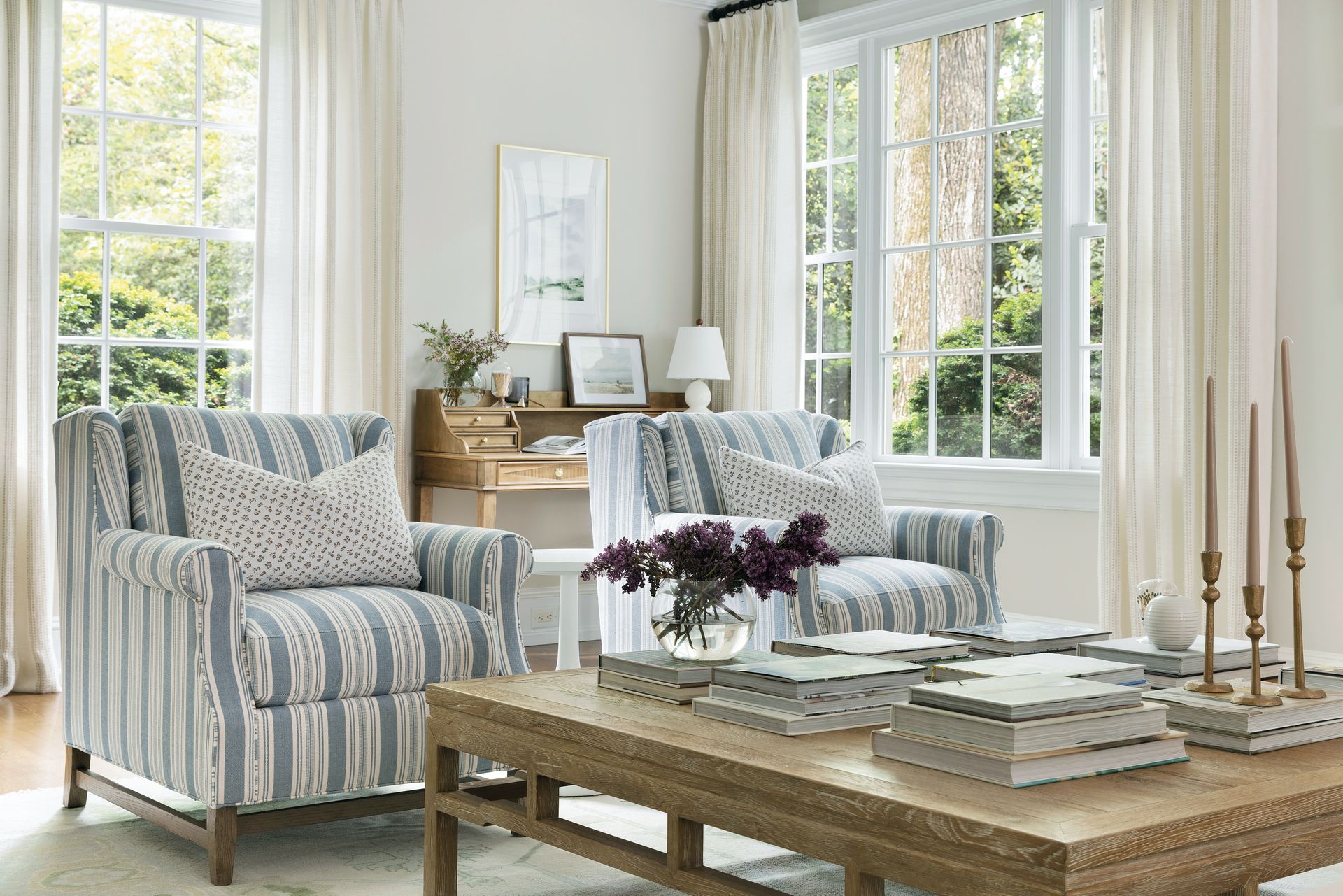 Two striped armchairs in a bright living room, with a coffee table, and large windows.