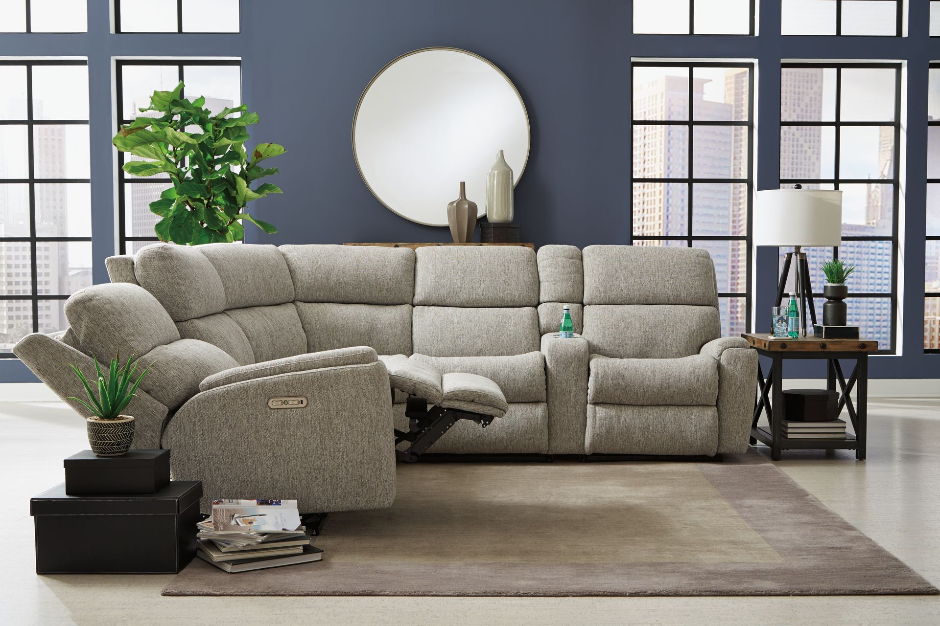 Gray sectional recliner sofa in a modern room with a rug and a side table.