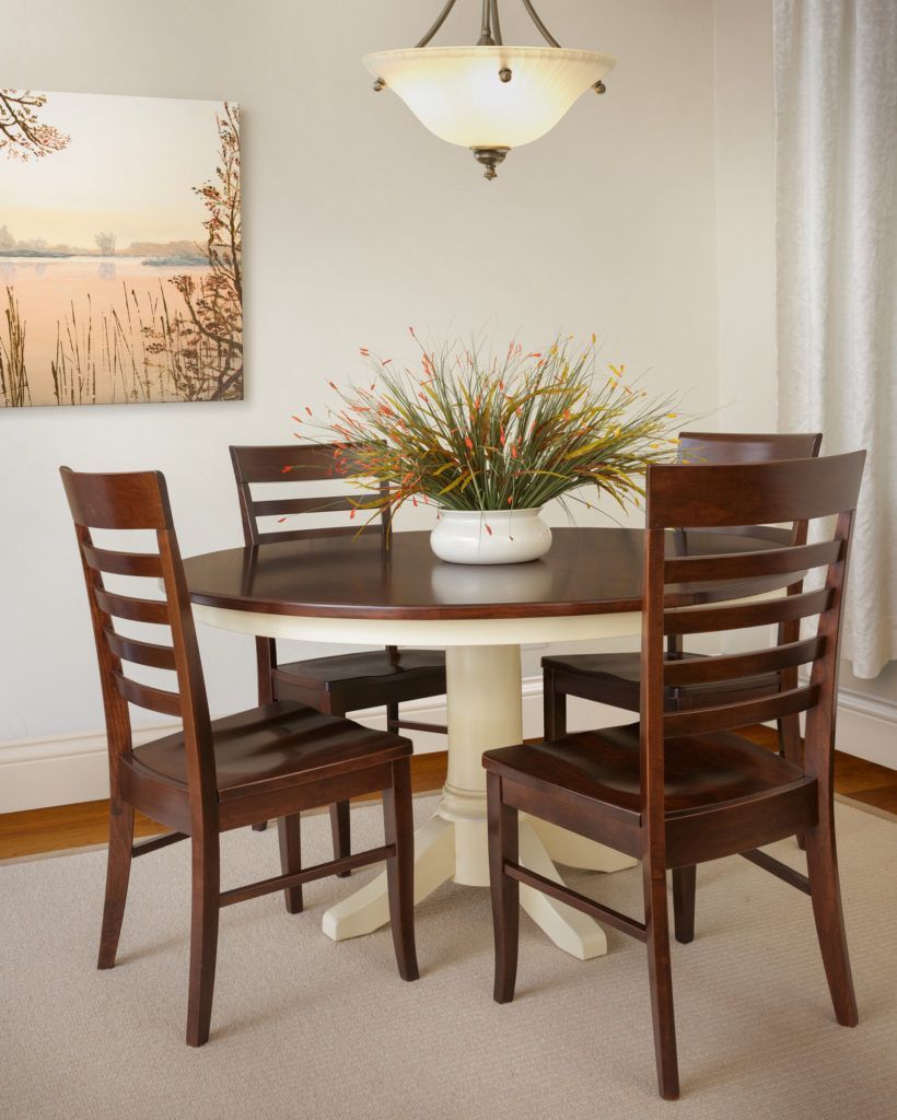 Round dining table with four chairs; artwork and plant centerpiece.