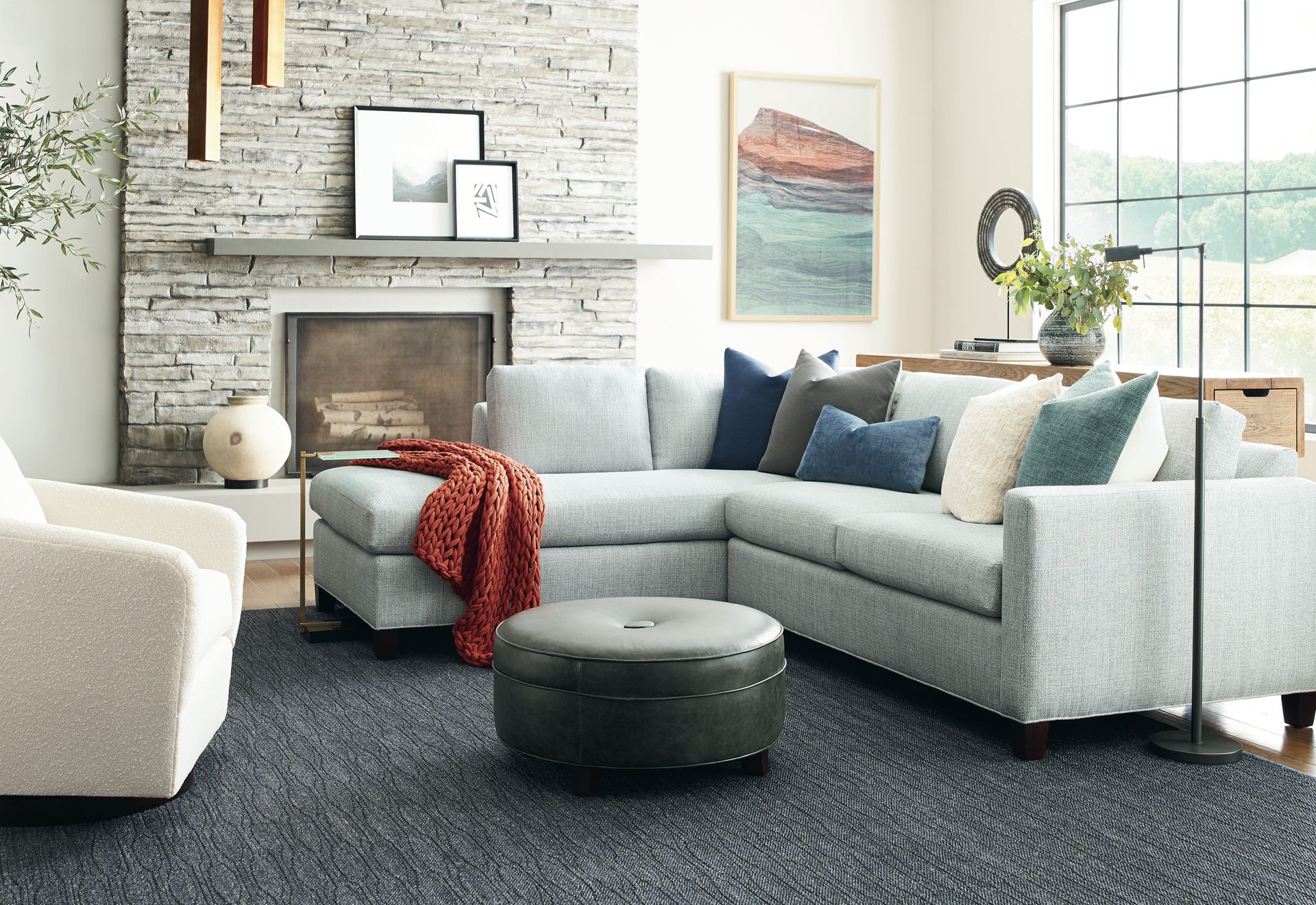 Living room with gray sectional sofa, stone fireplace, and patterned rug.