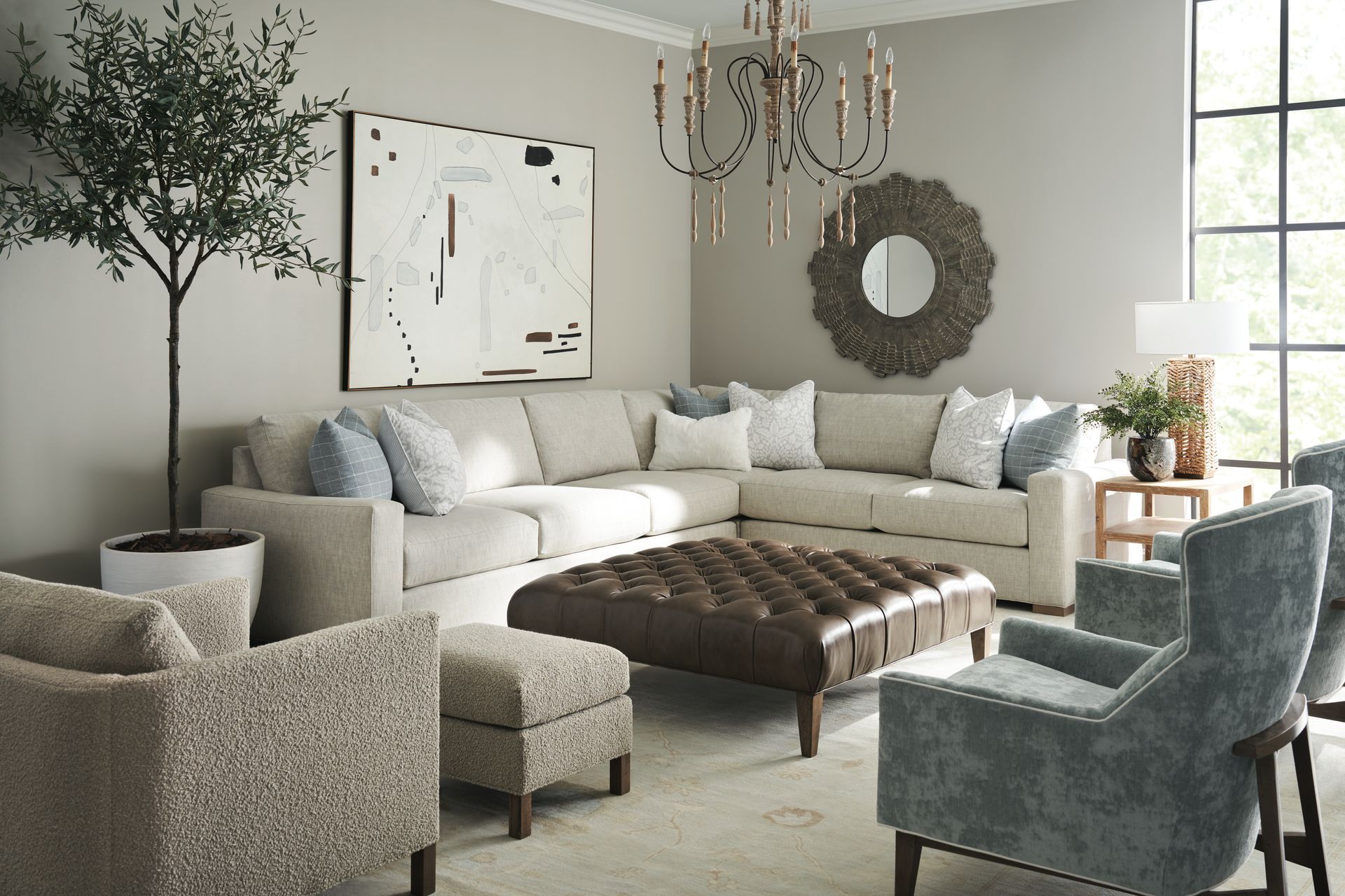 Living room with sectional sofa, armchairs, and ottoman; neutral color palette, natural light.
