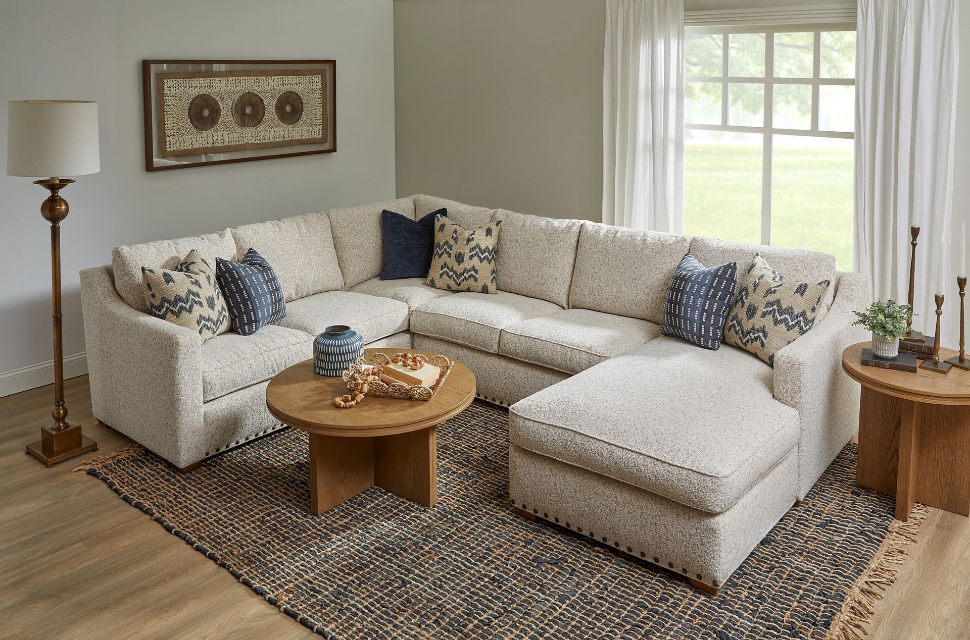 U-shaped beige sectional sofa in a living room, rug, coffee table, pillows, and decor.
