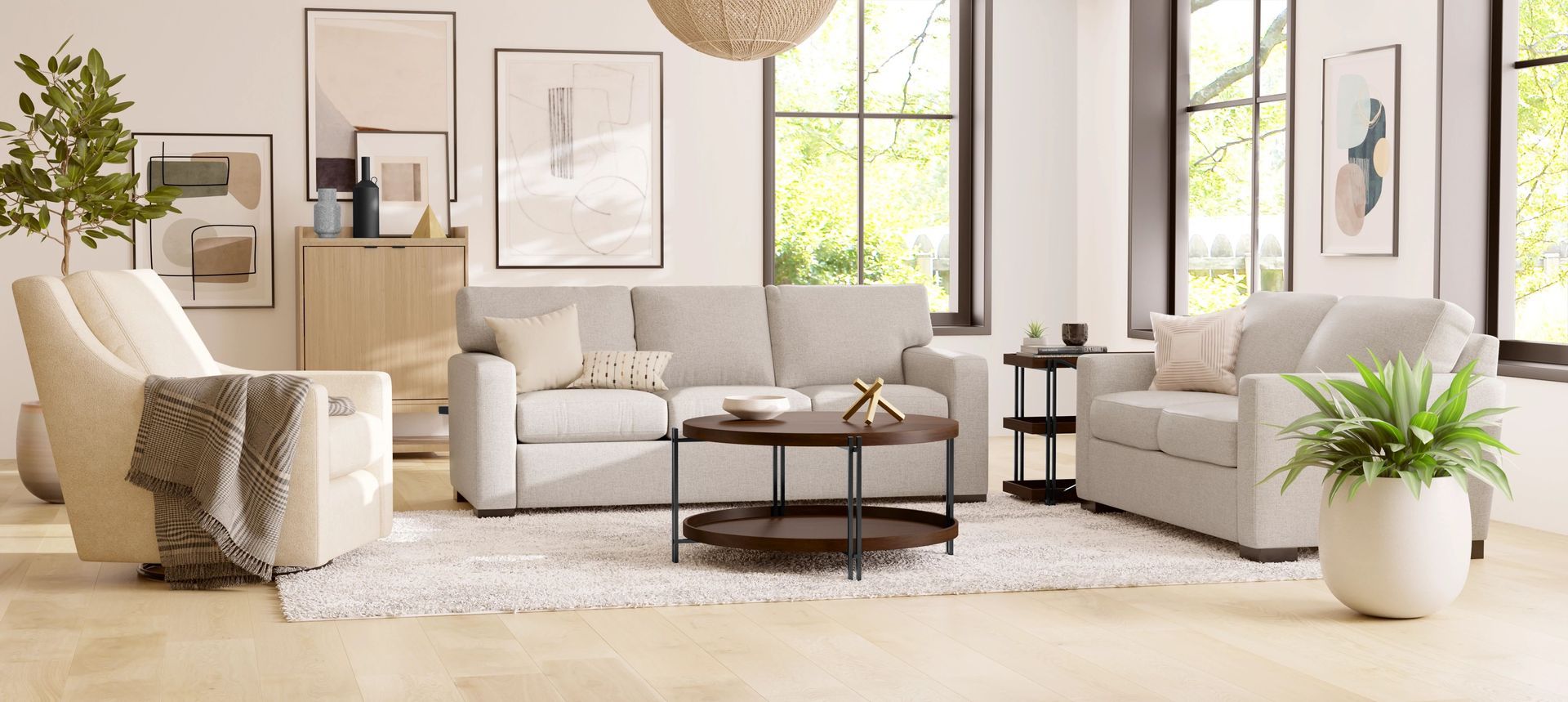 Living room with a light gray sofa, armchairs, coffee table, and large windows.