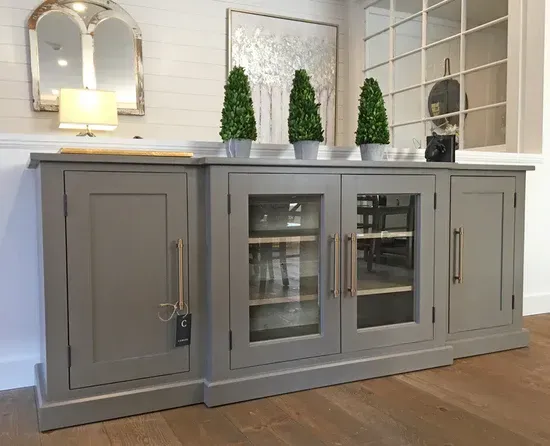 Gray buffet with cabinets and glass-door display, topped with potted plants.