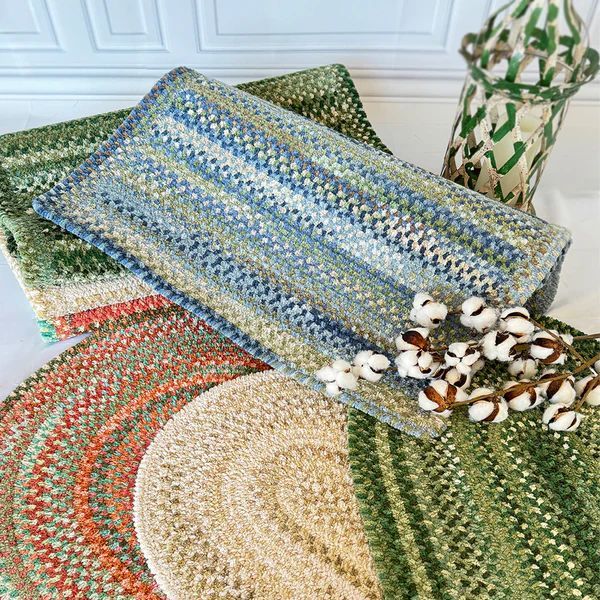 Pile of colorful knitted rugs and towels in shades of green, blue, and tan.