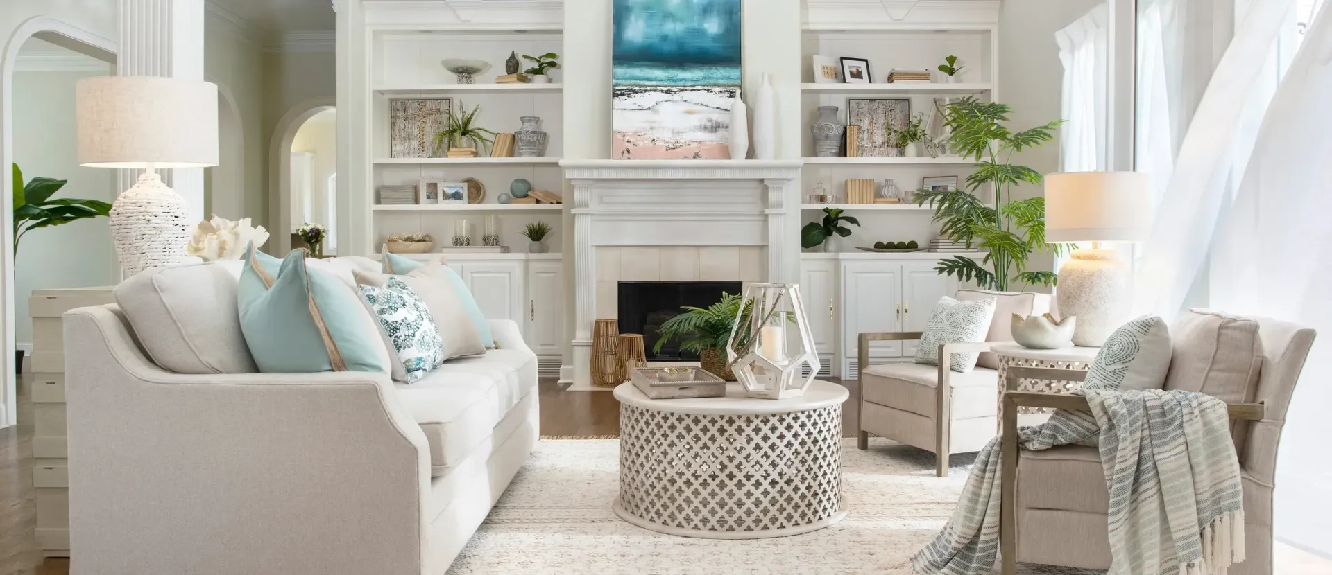 Living room with white sofa, blue and white pillows, fireplace, built-in shelves, and a patterned coffee table.