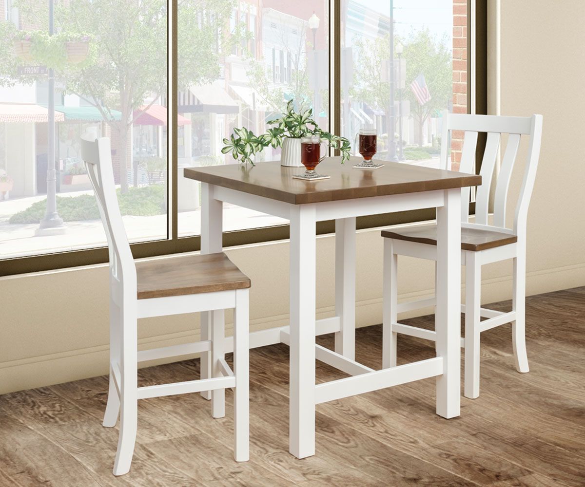 White and brown wooden square table with two matching chairs by a window, two drinks on table.