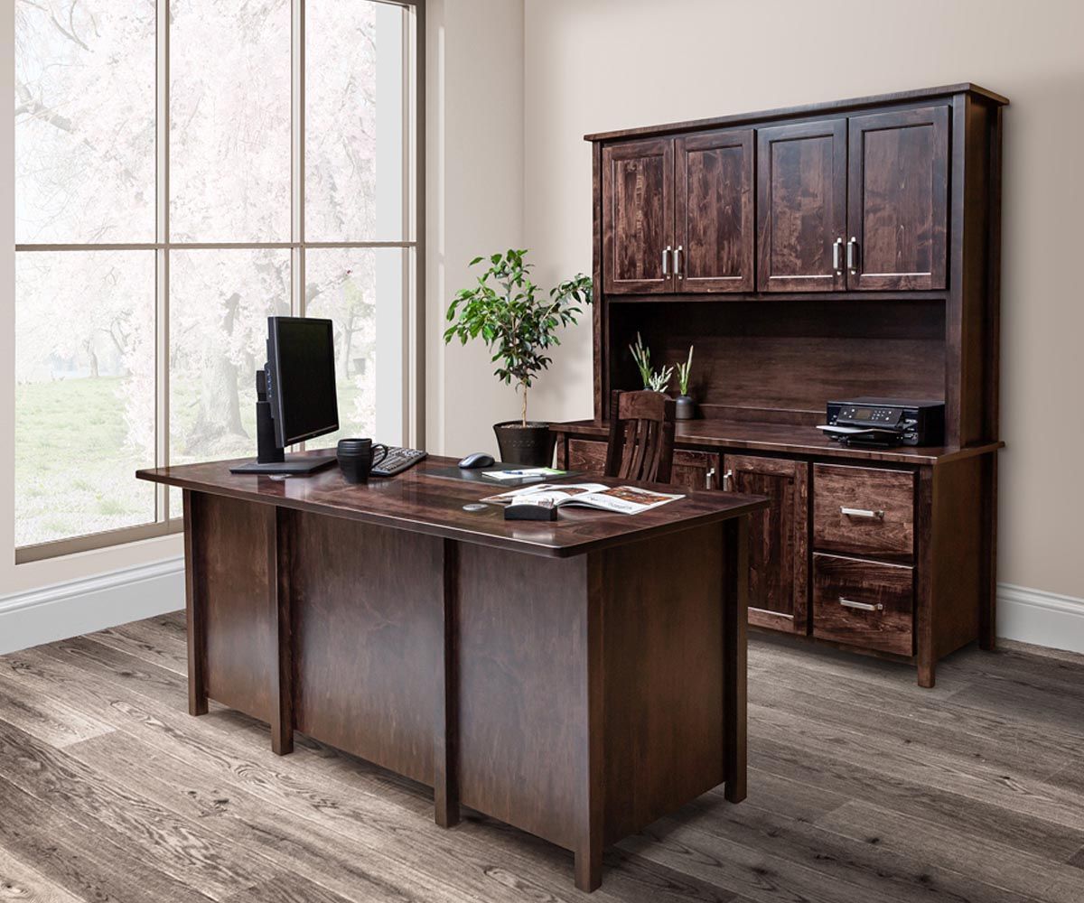 Wooden office furniture set in a home office: desk, hutch, chair. Dark wood, large window.