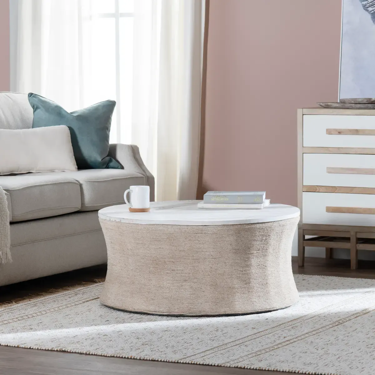 Round coffee table with textured sides and white top in a living room.