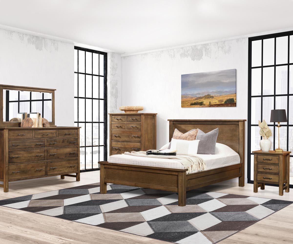 Bedroom with wooden furniture: bed, dresser, chest, nightstand. Diamond patterned rug on the floor.