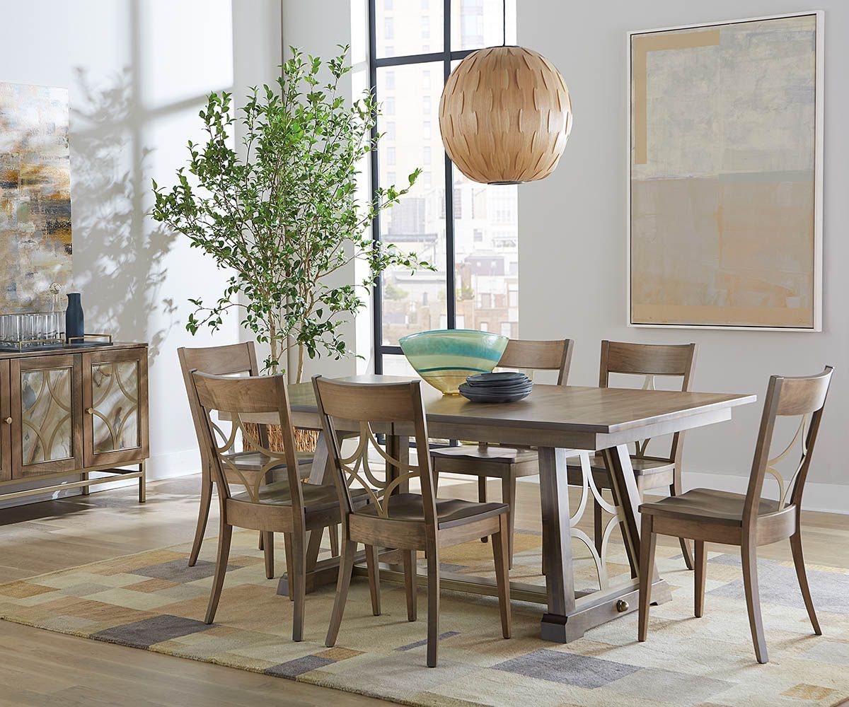Dining room with wooden table, chairs, decorative rug, and art. Neutral tones, natural light.