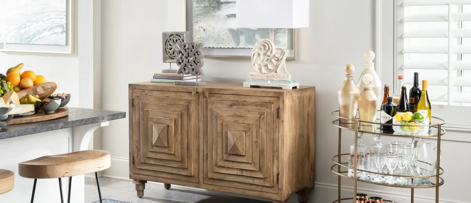 A room with a wooden cabinet, bar cart, and stools. White walls. Sunlight.