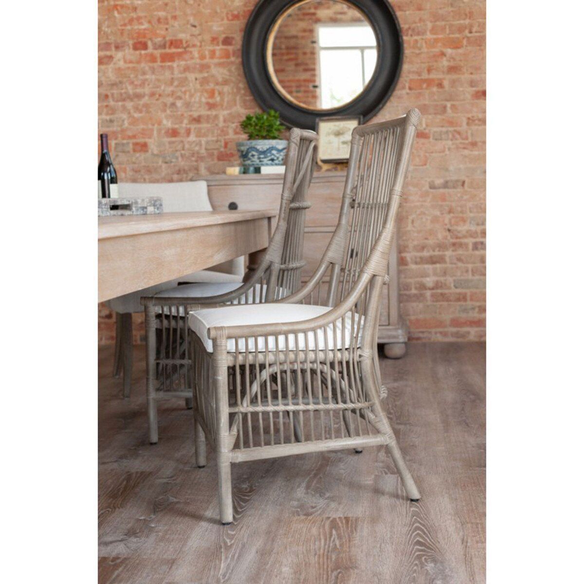 Two gray wicker dining chairs with white cushions at a light wood table, in a dining room.