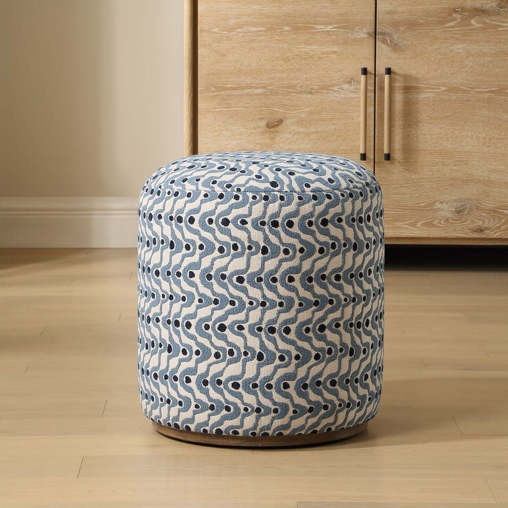 Blue patterned ottoman on a wooden base in front of a light wood cabinet.