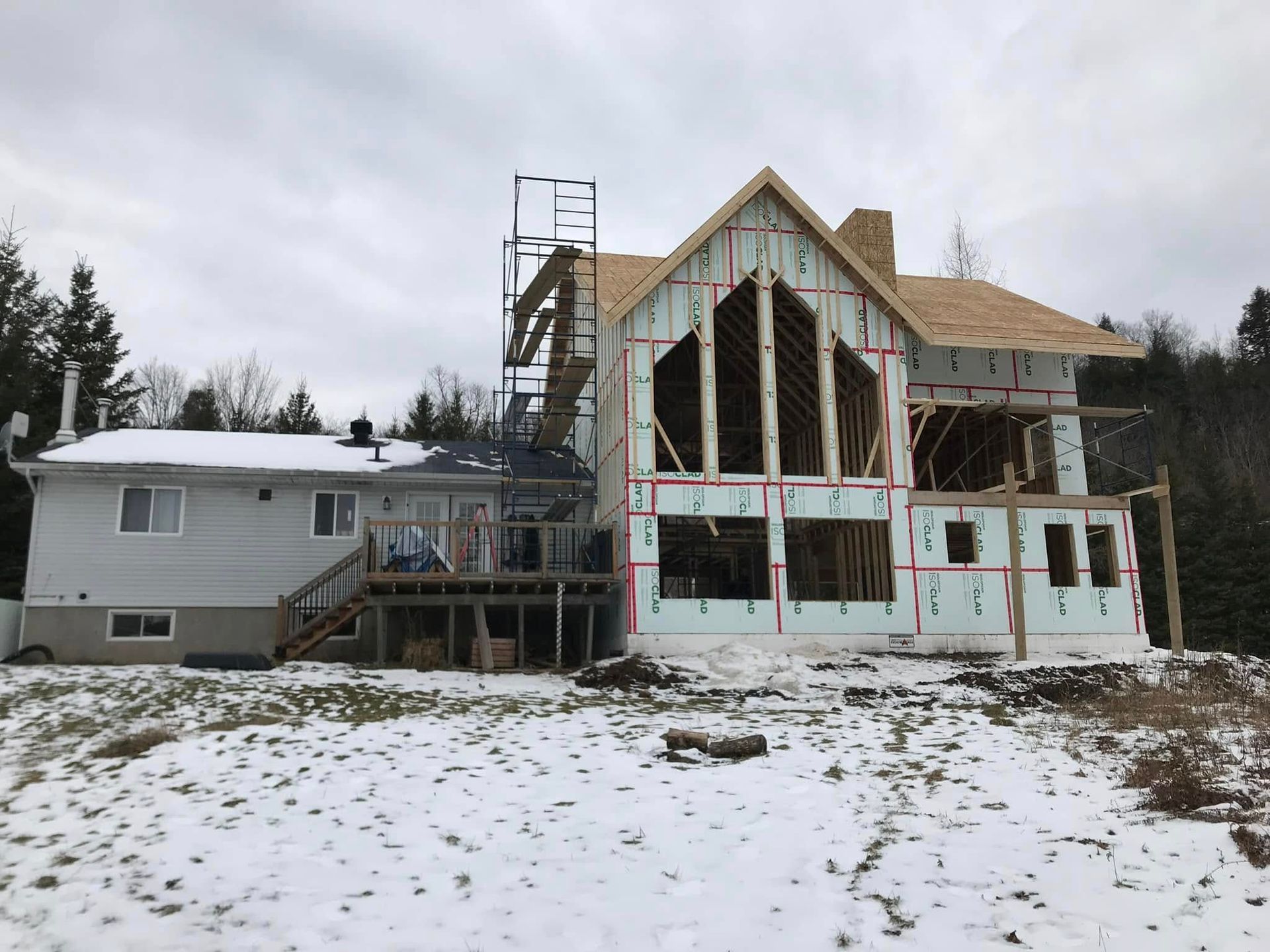 Une maison en rénovation avec une nouvelle extension de deux étages accolée à la structure d'origine, entourée d'une légère neige.