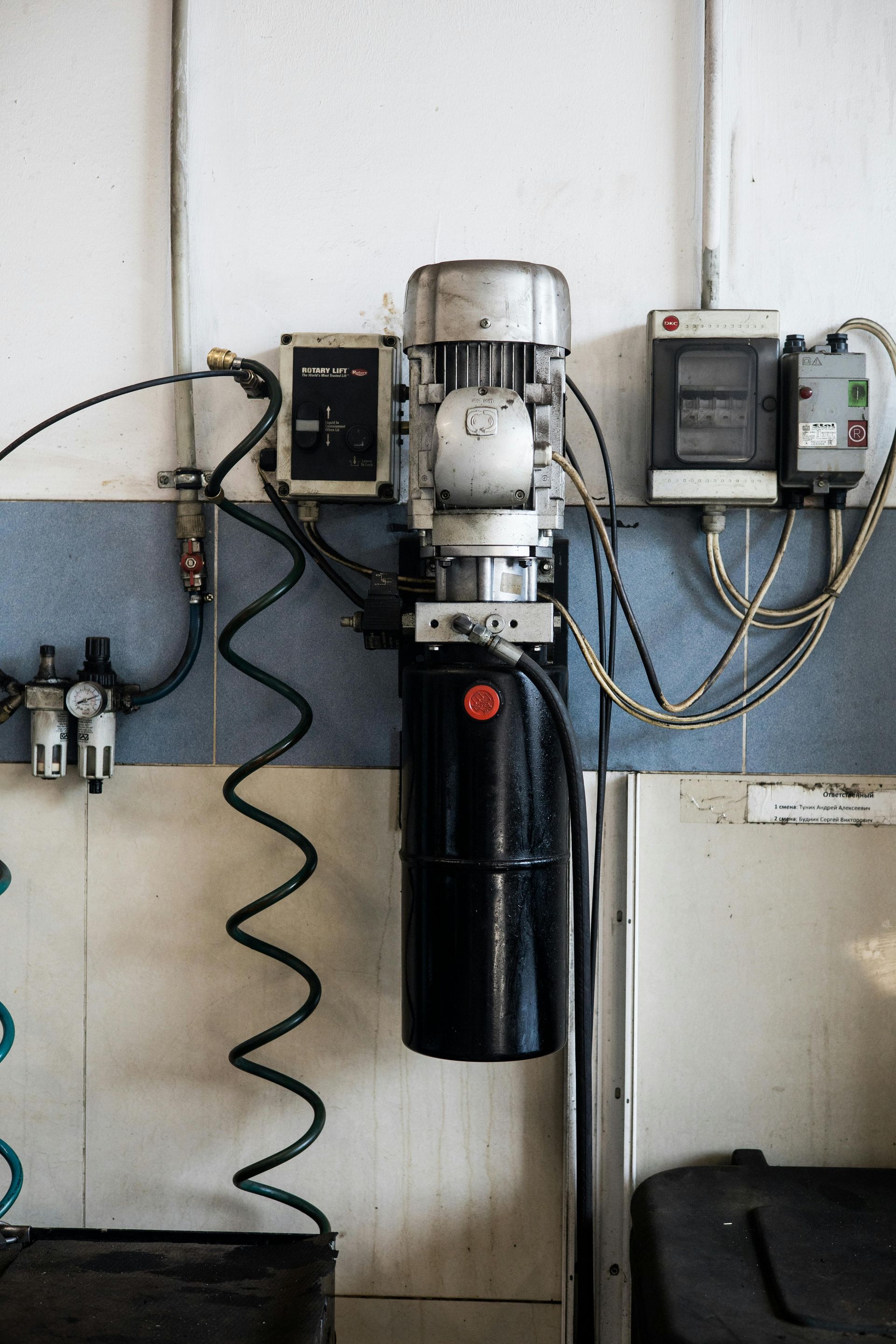 A black cylinder with a motor attached to it is hanging on a wall.