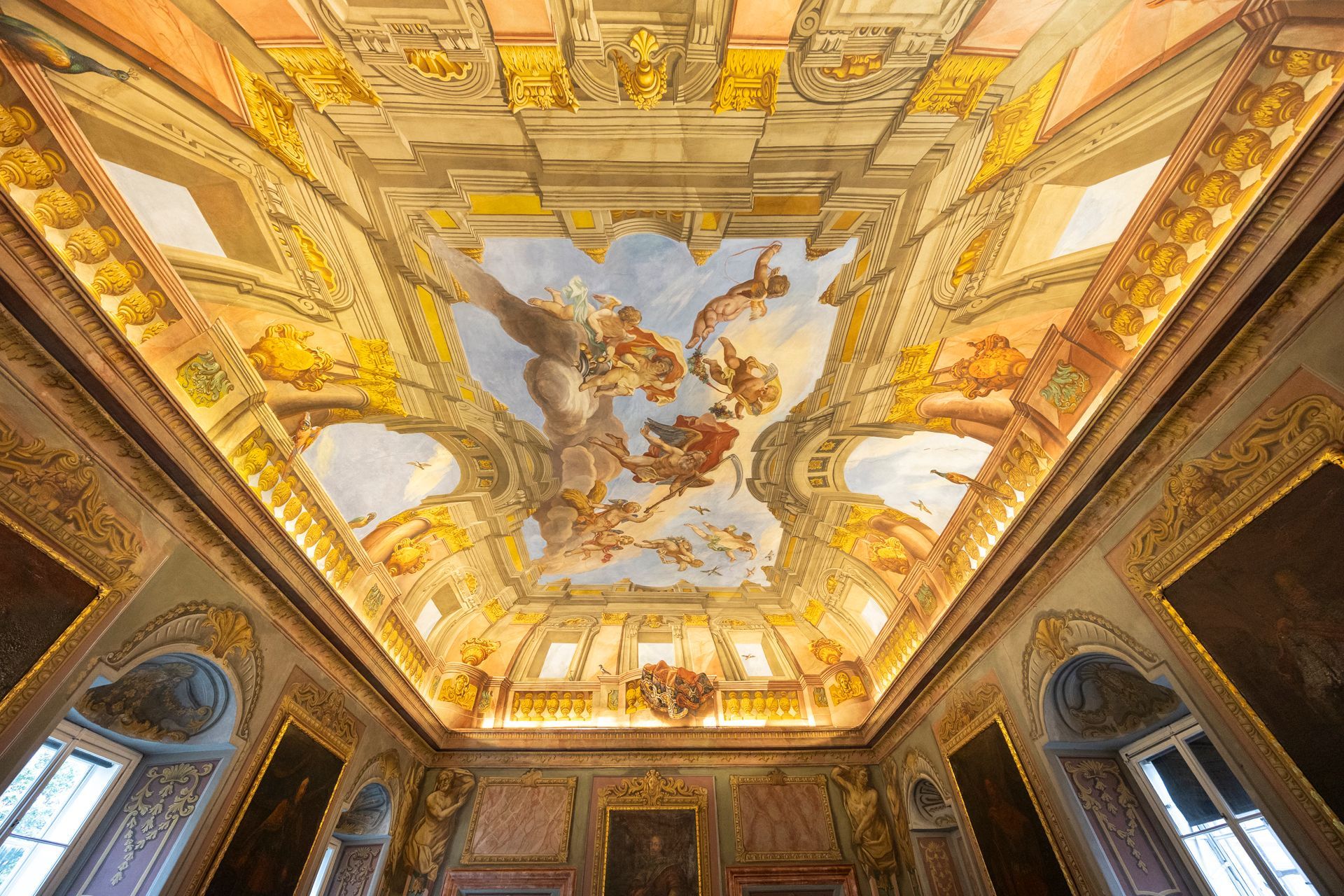 prunkvoller, goldverzierter Raum mit einem kunstvollen Deckenfresko, das Figuren am Himmel darstellt,