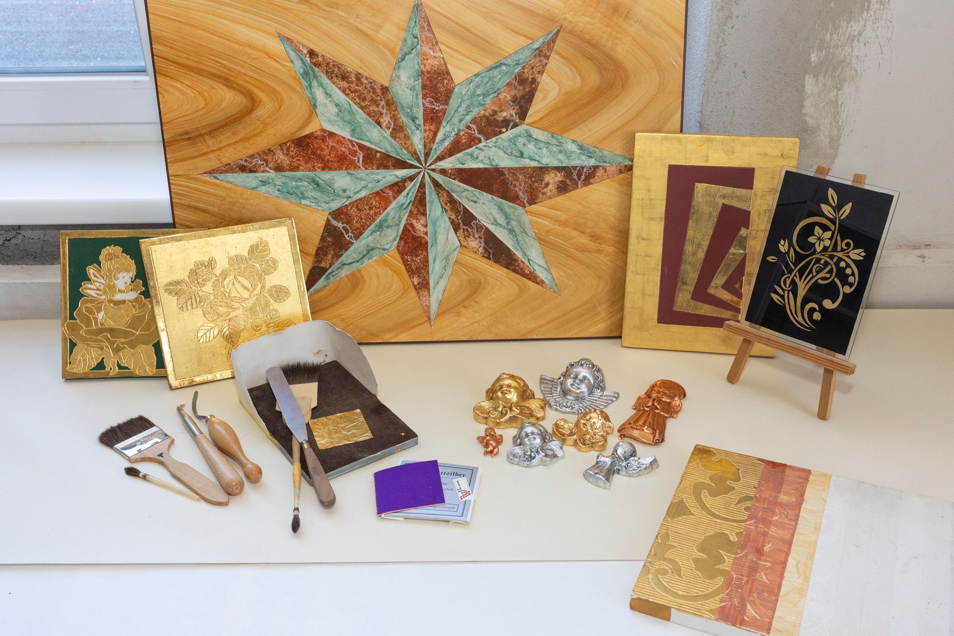 Blattgold-Kunstmaterialien, dekorative vergoldete Fliesen, ein sternförmiges Paneel und kleine Figuren