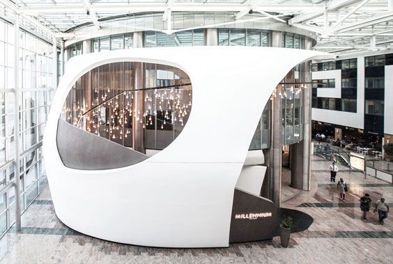 In einem modernen, lichtdurchfluteten Atrium befindet sich ein skulpturales, weißes, organisch geformtes Bauwerk