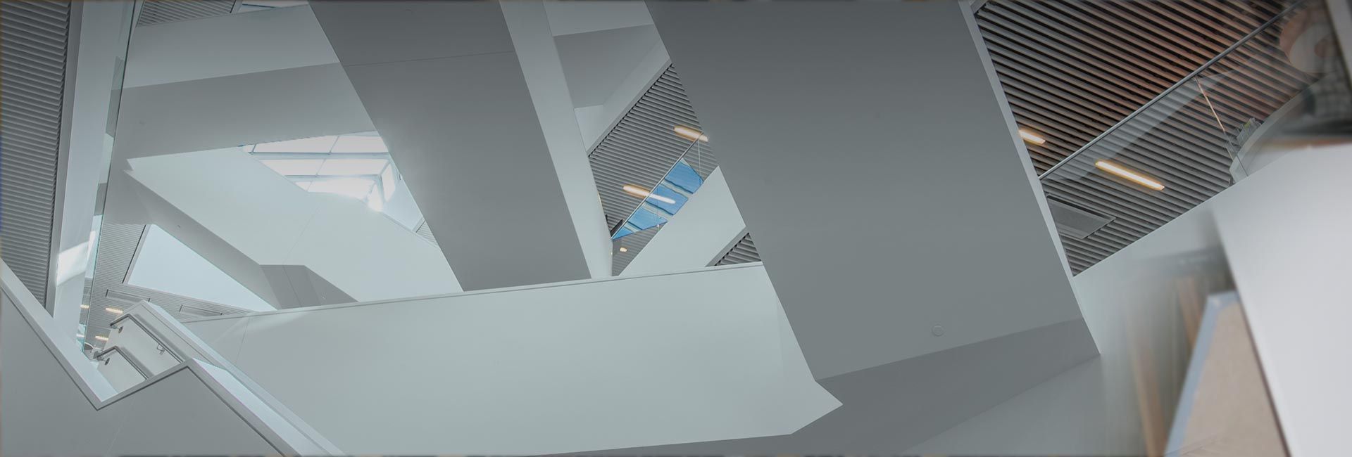 Eine Ansicht aus der Froschperspektive auf moderne, sich überschneidende weiße Architekturflächen eines Innenraums
