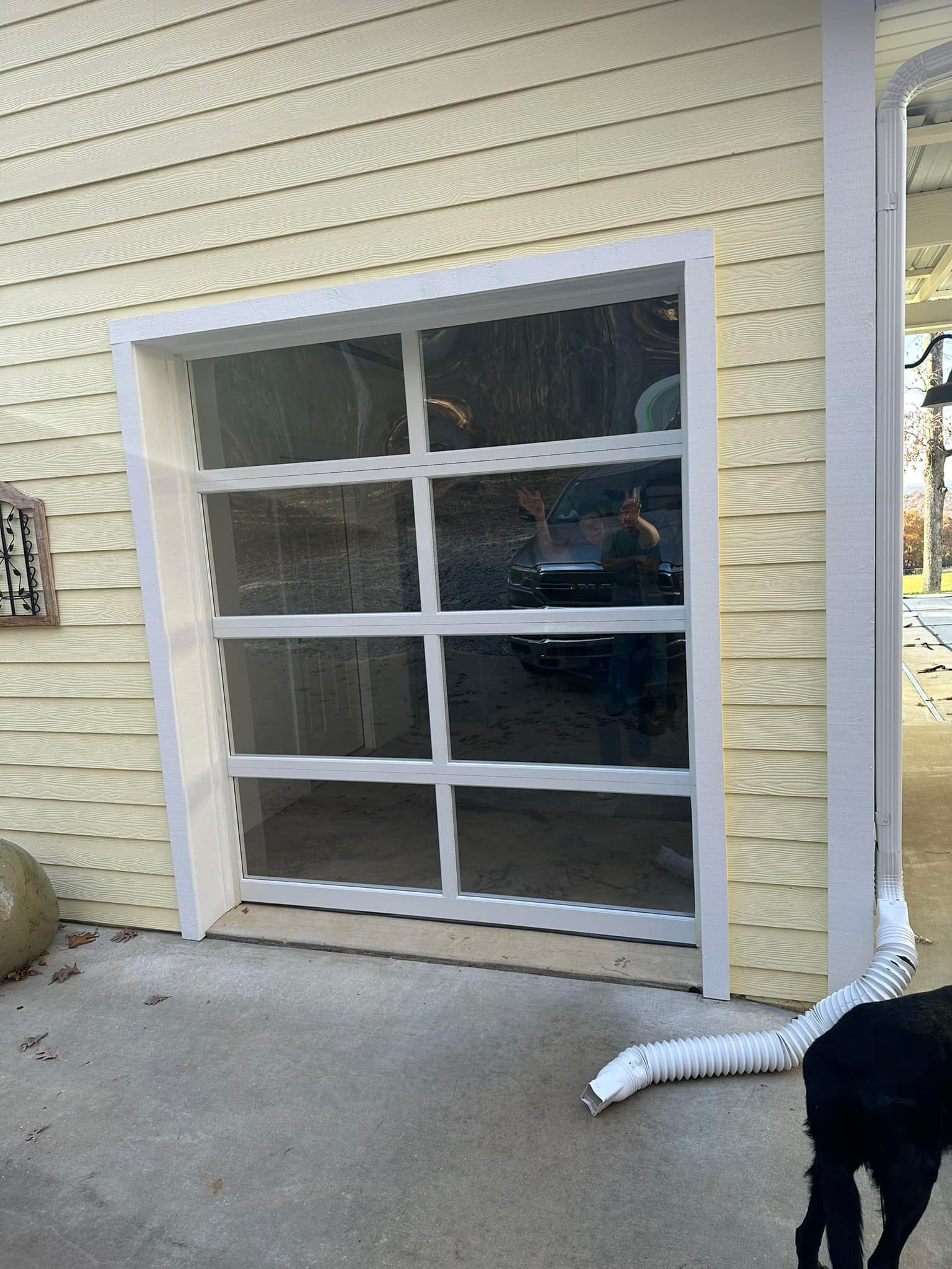 A white, multi-paneled, modern glass garage door installed in a yellow-sided building exterior.