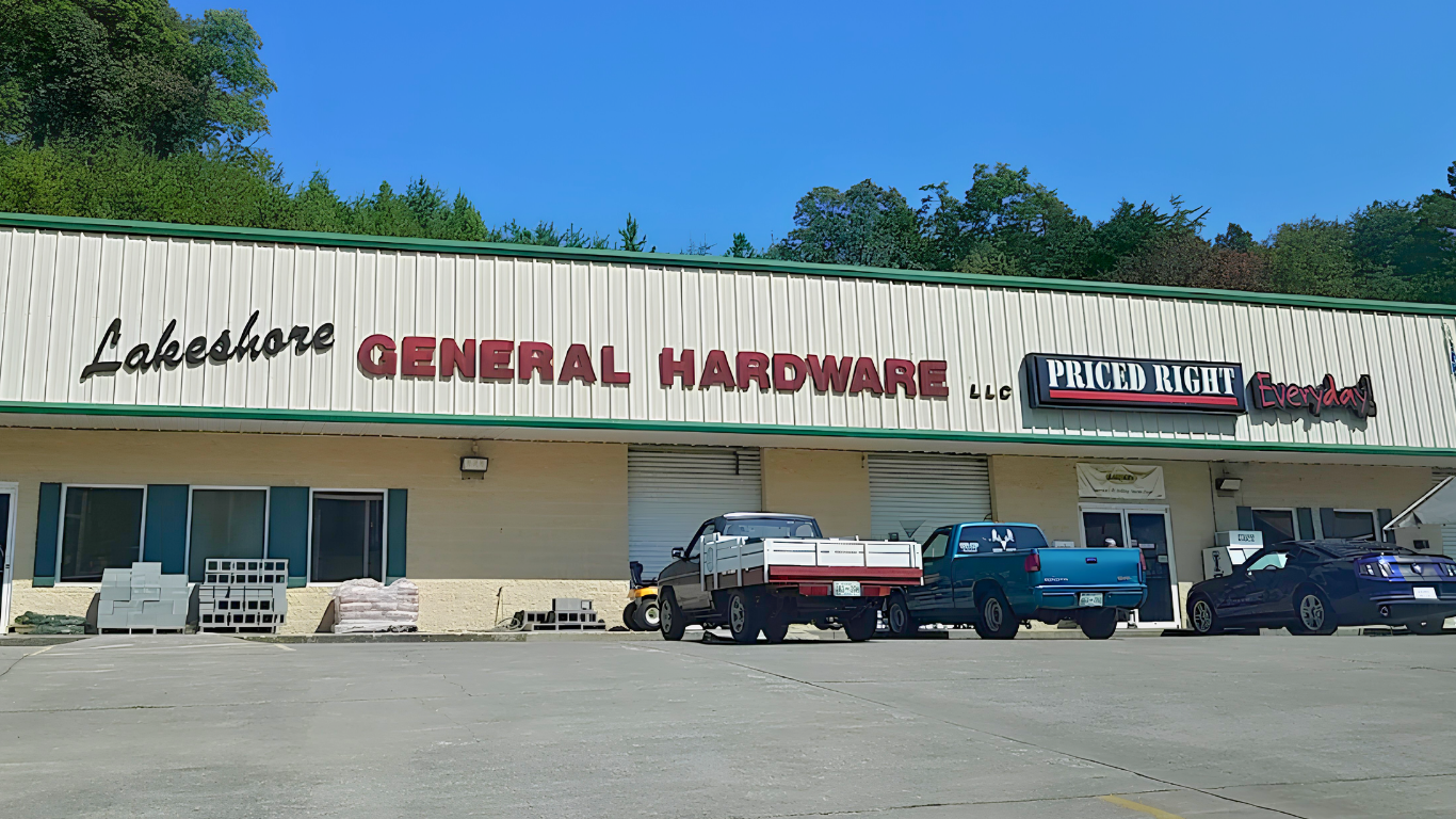 General hardware store storefront with parked vehicles under a clear blue sky