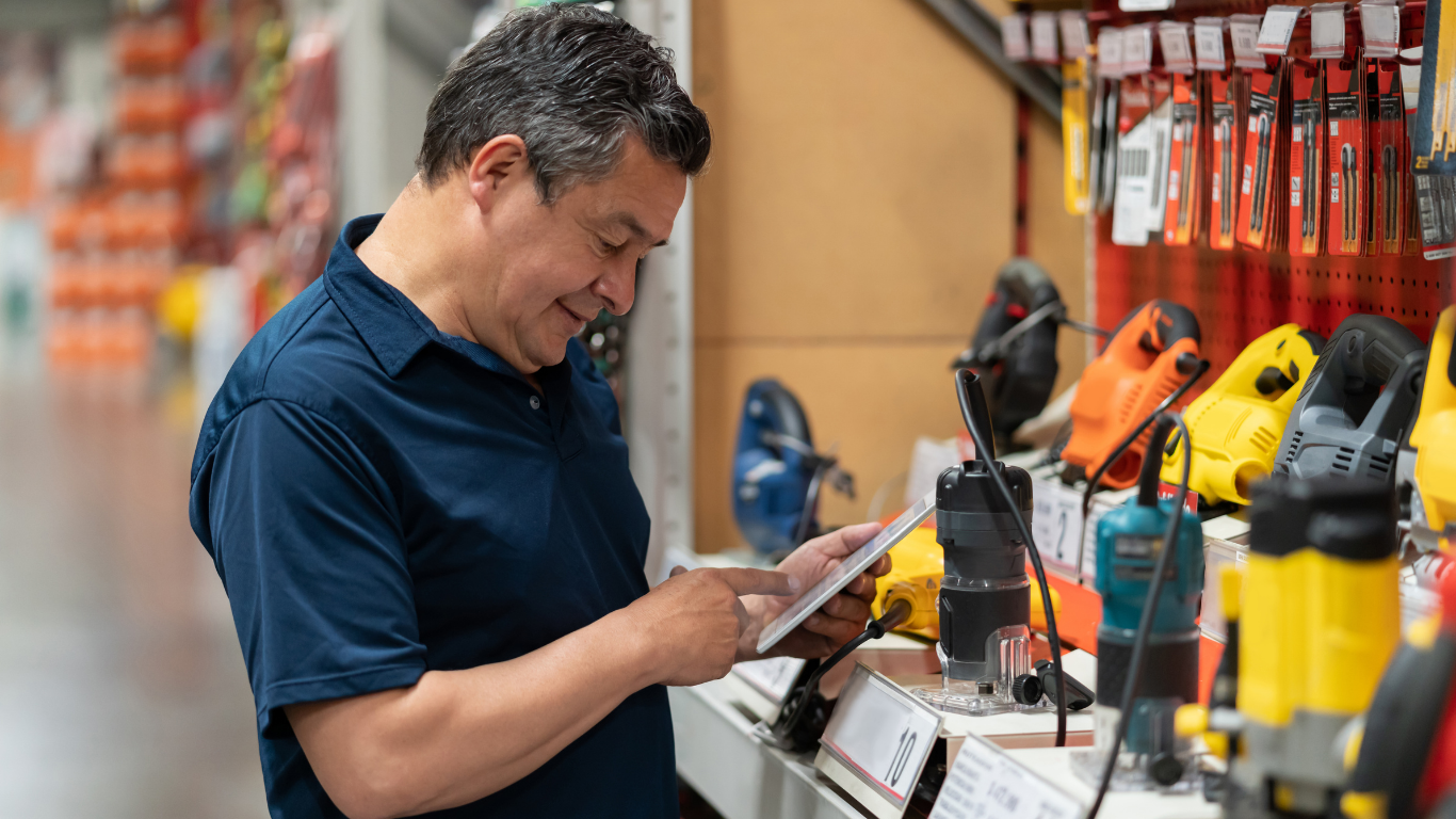 Man in navy shirt reading a brochure at a tool display in a hardware store