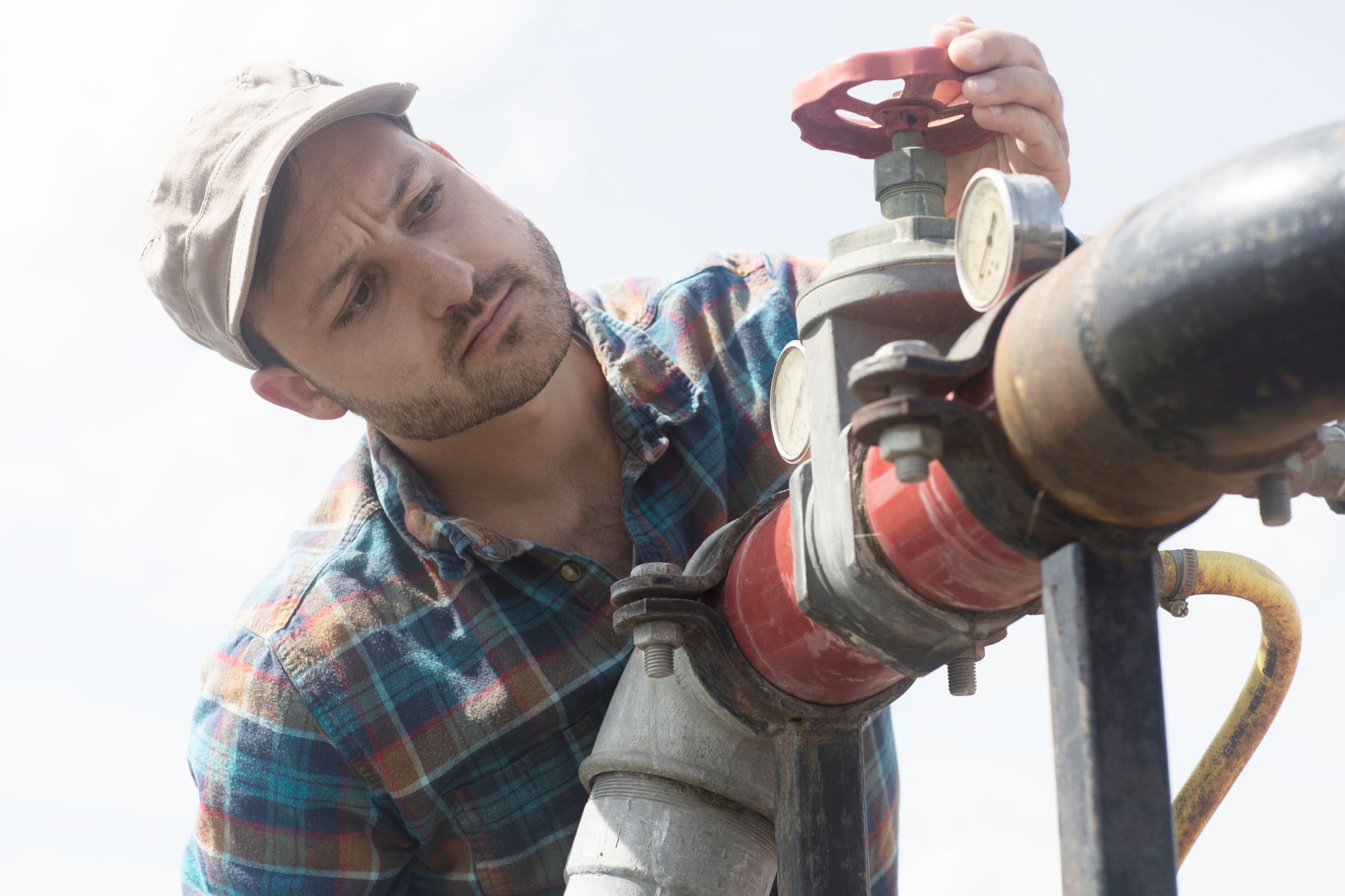 Man opening valve on industrial water well piping