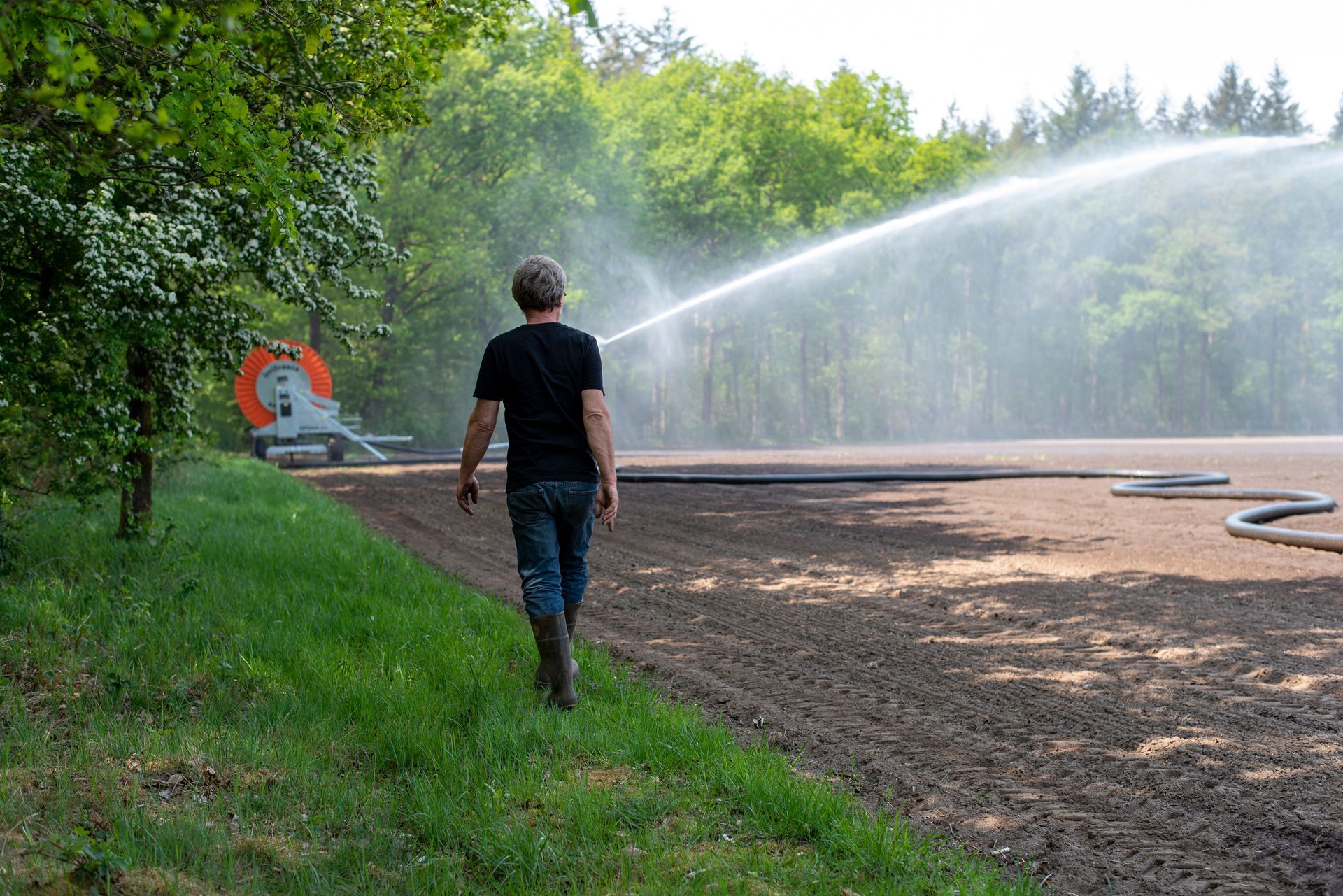 A man walks through a field looking over an irrigation system’s crops in a rural setting.