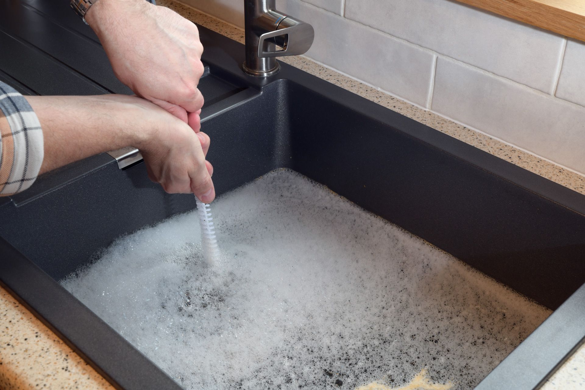A person is cleaning a sink with a brush.
