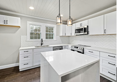 Bright white modern kitchen with island, black fixtures, and pendant lights