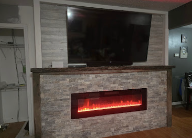 Living room fireplace with stone surround and mounted flat-screen TV, glowing red fire below