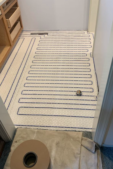 Bathroom floor with electric radiant heating cables laid in a serpentine pattern on subfloor.