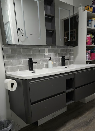 Modern bathroom vanity with double sinks, dark cabinets, gray tile backsplash, and mirrors above.