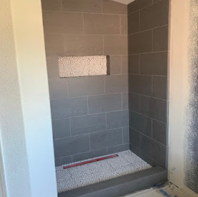 Tiled shower alcove with a curb, recessed niche, and red leveling strip at the base